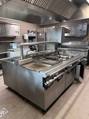 une grande cuisine professionnelle équipée d'appareils électroménagers et de plans de travail en acier inoxydable