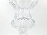 a clear glass vase on a stand on a white surface