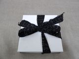 a small white box with a black ribbon on it