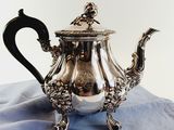a silver tea pot sitting on top of a blue cloth