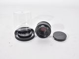 a glass cup and a lens on a white surface