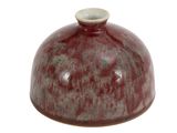 un vase rouge avec un couvercle vert sur fond blanc