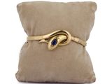 an image of a gold bracelet with a blue stone on a pillow