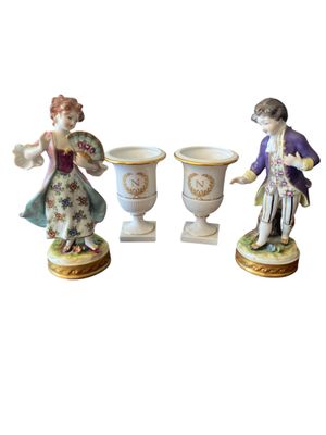 three porcelain figurines of a man and a woman with vases
