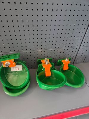 three green bowls with orange handles on a shelf