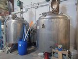 two large metal tanks in a warehouse with a blue bucket