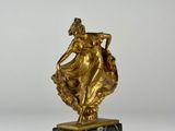 a gold statue of a woman holding a basket on a marble base