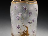 un vase en verre orné de fleurs violettes, posé sur une table