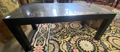 une table noire avec un plateau en verre posée sur un tapis