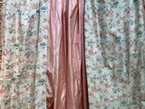 a pink dress hanging on a hanger in front of a floral curtain