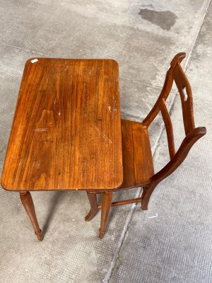 a small wooden table and two chairs on the sidewalk