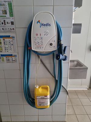 un tuyau bleu fixé au mur, à côté d'un bidon jaune
