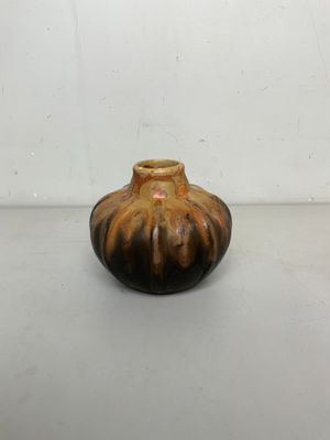 un petit vase brun posé sur une surface blanche