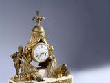 a gold clock sitting on top of a white table