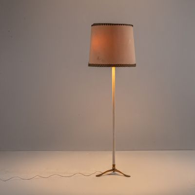le lampadaire est posé sur une surface blanche et est muni d'un abat-jour beige