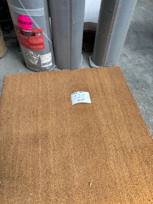 a brown door mat on the floor next to some rolls of tape