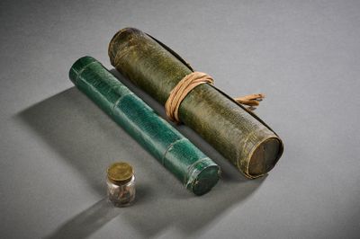 un vieux livre, un stylo et un rouleau de papier posés sur une table