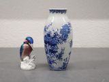 a blue and white vase with a bird figurine next to it