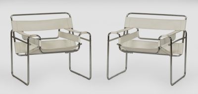 deux fauteuils en cuir blanc placés l'un à côté de l'autre sur une surface blanche