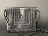 a silver purse sitting on top of a table next to a gray wall