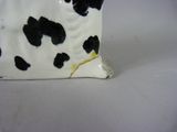 a white and black cow figurine sitting on a table