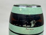 a green vase with black and white stripes on it
