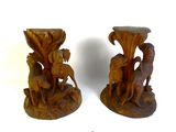 two wooden vases with animals on them on a white surface