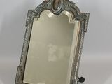 une photo d'un miroir argenté posé sur une table blanche