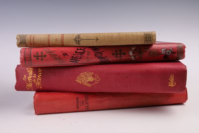 trois livres rouges empilés les uns sur les autres sur une surface blanche