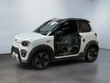 La petite voiture blanche est garée dans la pièce, les portières ouvertes.