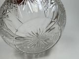 a clear glass bowl with a red handle on a white table