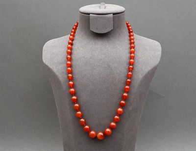 un collier de perles rouges sur un mannequin, muni d'un fermoir en argent
