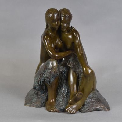 statue en bronze représentant un couple assis sur un rocher