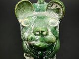 a green statue of a dog with a collar around it ' s neck