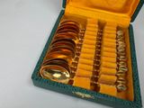 a green box with a bunch of gold spoons in it