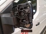 a hand that is holding a piece of metal in front of a white van