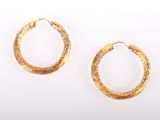 two pairs of gold toned hoop earrings on a white background