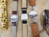 a lot of watches that are sitting on a wooden table