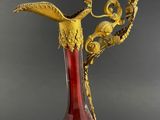a red and gold vase with a bird on top of it
