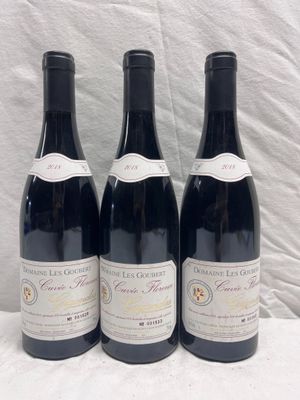 trois bouteilles de vin rouge sont alignées sur une surface blanche