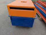 an orange and blue mail box sitting on the ground