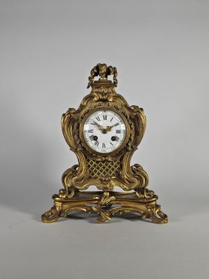 une horloge ancienne avec un cadre doré et un cadran blanc