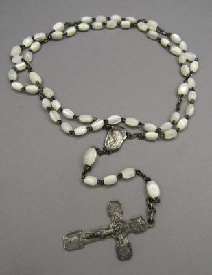 chapelet avec une croix en argent et des perles blanches sur fond gris