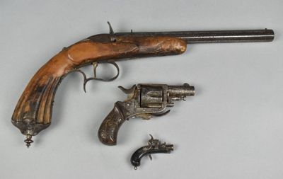 un vieux pistolet à crosse en bois et deux revolvers plus petits