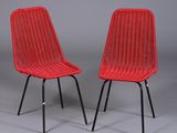 une paire de chaises en osier rouge avec des pieds en métal noir sur fond gris