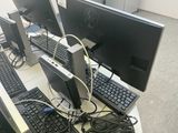 several computer monitors and keyboards on a table with wires and cords