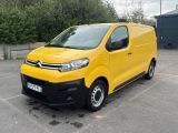 La camionnette jaune est garée sur un parking, avec des arbres en arrière-plan.