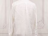 the white shirt is on a mannequin stand in front of a white wall