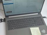 un ordinateur portable posé sur une table, avec un bloc-notes dessus
