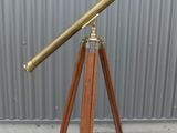 an antique brass telescope on a wooden tripod stand